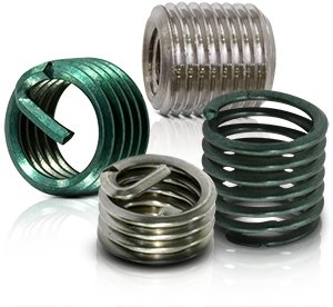 Diversi inserti filettati metallici in verde e argento per la riparazione di filettature.